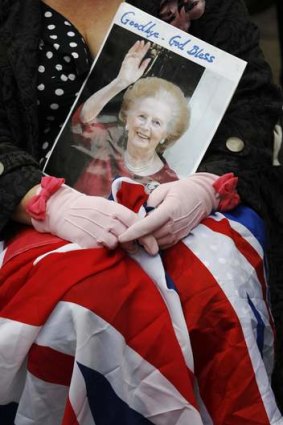 A spectator waits for the funeral procession of former British prime minister, Margaret Thatcher.