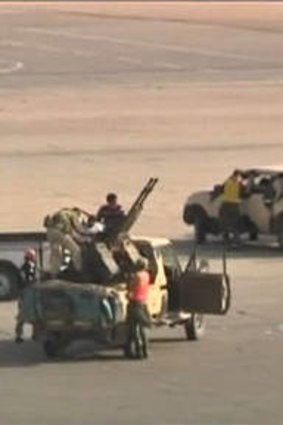 Armed militia in military pick-up vehicles on the tarmac of Tripoli international airport.