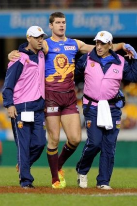 Jonathan Brown of the Lions is assisted from the field in Round 13.
