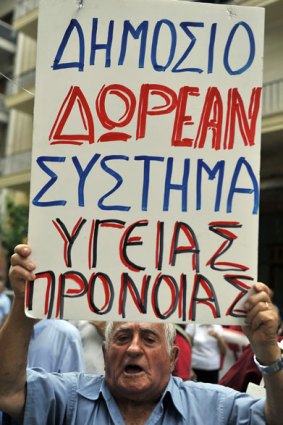 A Greek pensioner displays a placard which translates as ' Free public health and care system'  as he demonstrates in front of the Ministry of Health and social insurance in Athens. <i>AFP/ Louisa Gouliamaki</i>