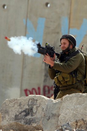 An Israeli soldier fires at Palestinian stone-throwers at the Qalandia checkpoint between Ramallah and Jerusalem.