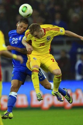 Jose Holebas (L) of Greece jumps for the ball with Alexandru Maxim of Romania.