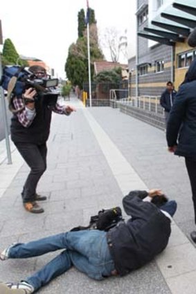 Unconscious &#8230; Channel Nine cameraman Mario Conti on the footpath after being attacked outside court yesterday.