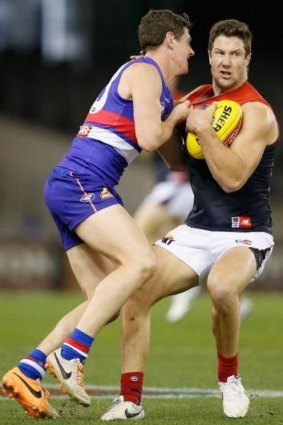 James Frawley of the Demons (right) tries to shrug off a tackle against the Western Bulldogs.