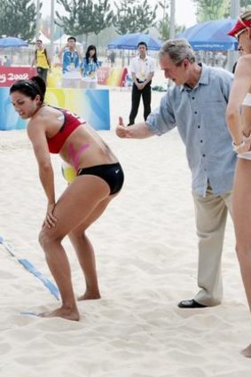 Then US-President George W Bush pats the back of US women's beach volleyball team player Misty May-Treanor (left) while visiting the Chaoyang Park Beach during the 2008 Beijing Olympics.