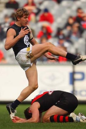 Down and out: Carlton's Tom Bell takes his kick over the back of Bomber Jobe Watson.