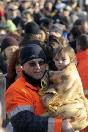A rescue worker carries a child as they arrive at Porto Santo Stefano.