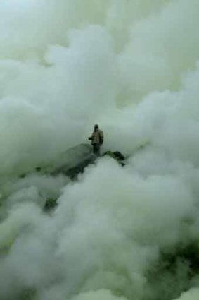 A worker gathers sulphur from a crater in East Java.