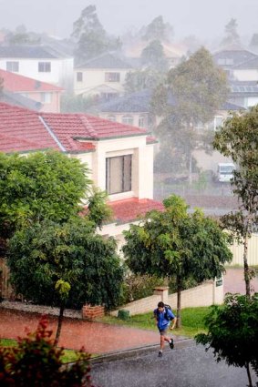 A student runs home for cover during a sudden downpour of rain and hail in Beaumont Hills.