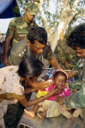 Sri Lankan army officers attend an ethnic Tamil child injured allegedly by gunfire from Tamil Tiger rebels near the war zone in northern Sri Lanka.