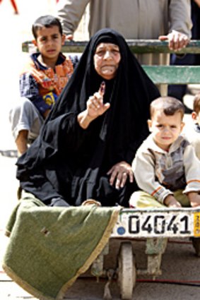 An Iraqi woman shows her ink-stained finger as proof she defied attacks to cast her ballot in Baghdad's Sadr City.