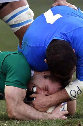 Cian Healy of Ireland  is tackled by Salvatore Perugini.