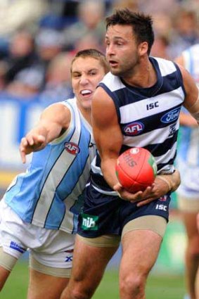 Geelong's Jimmy Bartel is about to be tackled by North Melbourne's Jamie MacMillan.