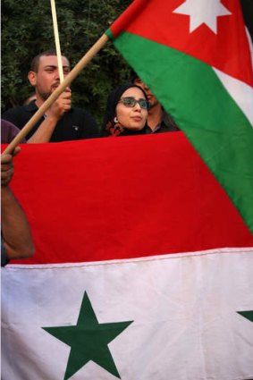 Protesters wave Jordanian and Syrian national flags aoutside the Friends of Syria conference, in Amman, Jordan, Wednesday, May 22, 2013.