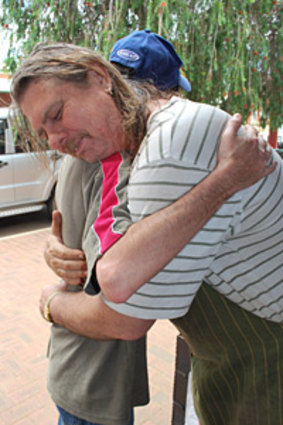 A friend consoles fruit shop owner Tom Carter (right), who lost his home and orchard in the Toodyay fires.