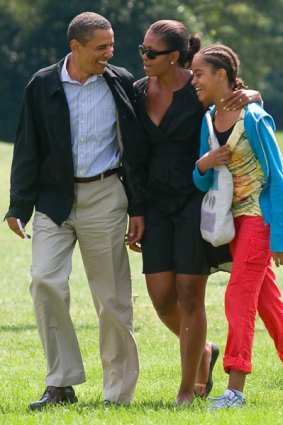 Barack, Michelle and Malia Obama walk across the South Lawn of the White House.