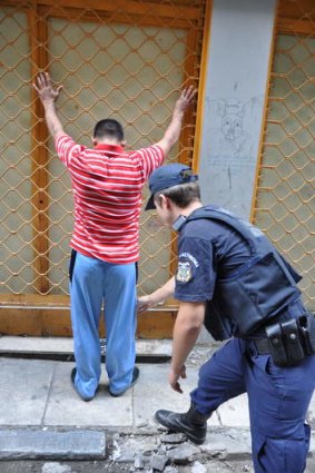 Greek tragedy ... An Athenian policeman checks a foreigner for ID papers.