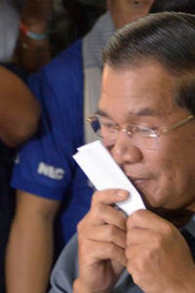 Cambodian Prime Minister Hun Sen kisses a ballot at a polling station during the general election, in Kandal province.