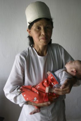 A caretaker holds a malnourished infant at an orphanage in Chongjin city, North Korea.