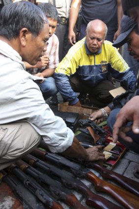 Plain-clothes Indonesian police count weapons, originally stored for guards, that were taken by inmates in the riot.