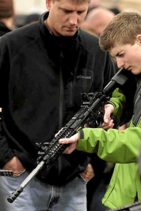 Father and son inspect a semi-automatic assault rifle for sale at a US gun show in January.