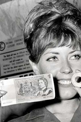 At the dawn of decimalisation in 1966, bank worker Ruth Thom holds up a holey dollar and the first Australian dollar bill.