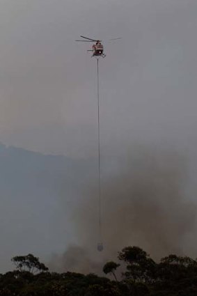 A water-bombing helicopter targets a fire encroaching on a property near Pretty Beach.