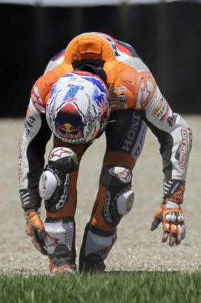 Casey Stoner grabs his injured ankle after the crash.