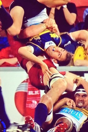 Brumbies halfback Nic White is flipped by Queensland Reds flanker Liam Gill.