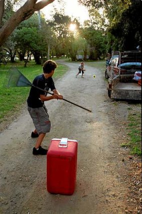 Children play cricket with improvised kit.