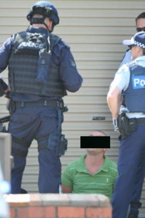 Police speak to a man handcuffed outside the Black Hill property following a five-hour stand-off.