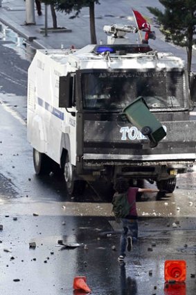 A demonstrator throws a rubbish bin at an armoured police vehicle during a protest against Turkey's Prime Minister in central Ankara.