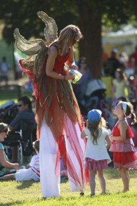 A fairy queen towers over two youngsters at Yarra Park.