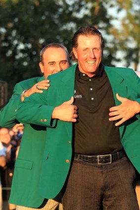 Angel Cabrera of Argentina presents Phil Mickelson with the famous green jacket.