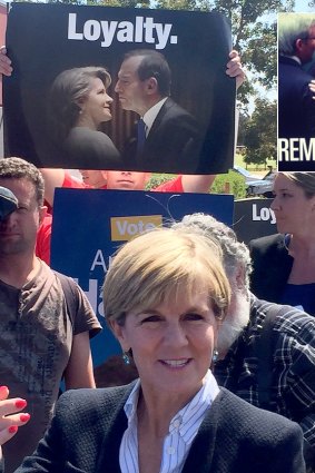 Julie Bishop with Loyalty sign in background as voting takes place in Canning. Inset, the original attack ad on Labor.