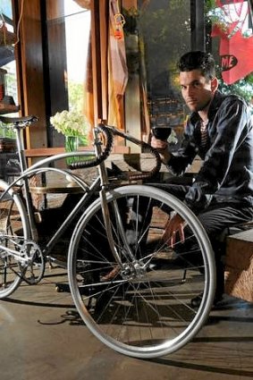 At the New Acton cafe, "Mocan & Green Grout", co-owner, David Alcorn, inside the cafe, with an example of the "Goodspeed" brand of bicycles they produce and sell.