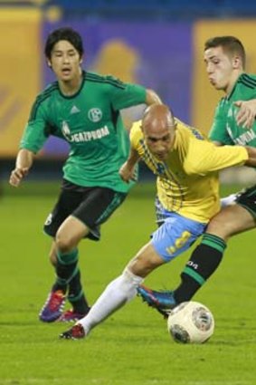 Mark Bresciano, playing for Qatar's Al-Gharafa club, fights for the ball with Schalke 04's Atsuto Uchida (left) and Donis Avdijaj during a friendly match in Doha in January.