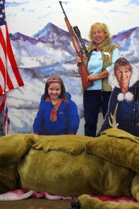 Gunning for a photo-op: A visitor to the Brooklyn Waterfront Artists Coalition in New York  poses  with  cardboard cutouts of  Republican vice-presidential candidate Sarah Palin and daughter Piper in an installation by artist Dawn Robyn Petrlik.