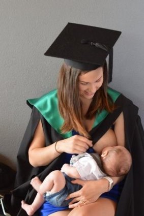 Jacci Sharkey breastfeeding her son while wearing her graduation robe.