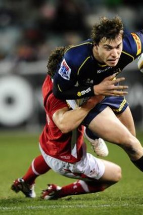 Brumbies player Cam Crawford is tackled by a Welsh defender.