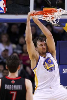 Andrew Bogut dunks while Andrea Bargnani of the Toronto Raptors looks on during the second quarter of the NBA game in Oakland, California.