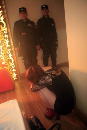 Chinese police watch over a female suspect during an anti-prostitution raid  in Dongguan earlier this month.