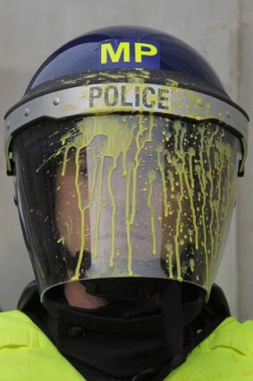 A riot police officer spattered by paint.