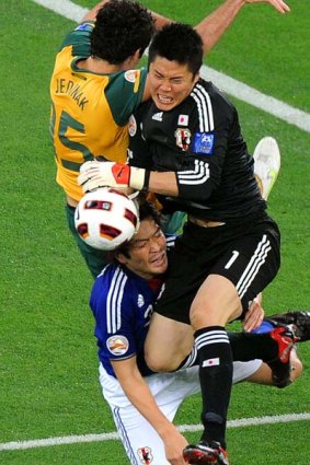 Japan's goalkeeper Eiji Kawashima and defender Daiki Iwamasa (bottom) challenge Australia's midfielder Mile Jedinak.