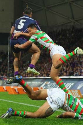 Dylan Farrell of the Rabbitohs falls to the ground injured as Mahe Fonua of the Storm and Andrew Everingham of the Rabbitohs compete for a high ball.