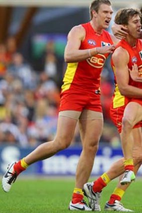 Sam Day, Seb Tape and Trent McKenzie of the Suns celebrate a goal against Collingwood.