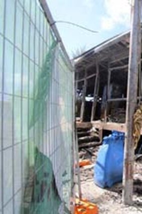 Still reeling: Workers extinguish tend to the destroyed facilities at Nauru after more than 100 asylum seekers rioted.