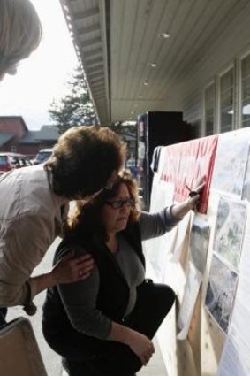 Searching for loved ones: A resident looks at aerial photos of the mudslide for her missing husband's car.