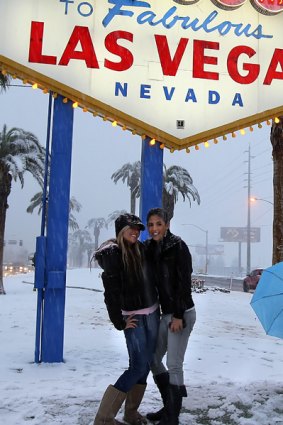 Two girls take their turn to pose in the snow next to the  famous Las Vegas sign at one end of the strip.