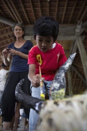 A child from a remote Indonesian community paints puppets during a visit by members of Melbourne's Polyglot Theatre.